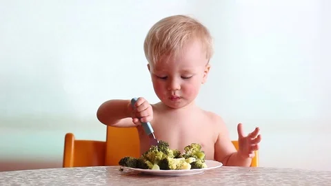 Baby eats with pleasure steamed broccoli by fork and hand, happy kid Video stock 88087579