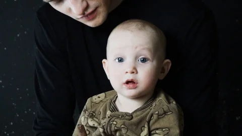 The baby eats sweets. The child sits in the arms of his father. Slow motion. Stock Footage 88871287