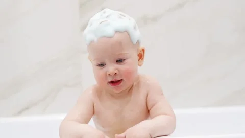 Baby enjoys bath time with bubbles in a bathtub Stock Footage 335941553