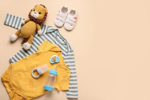 Baby essentials flat lay with bodysuits, lion toy, shoes, pacifier, and bottl Stock Photos