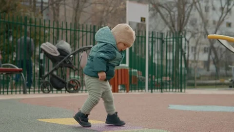 Baby explores playground while taking first steps and learning to play Stock Footage 303578687