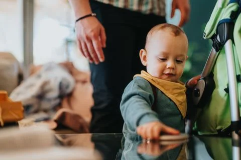 Baby exploring a table while supervised in a cozy home environment with warm Stock Photos