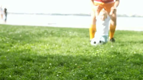 Baby with father playing with soccer ball on the grass Stock Footage