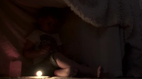 Baby with flashlight reading Stock Footage 76605757
