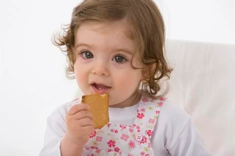 Baby girl eating cookie, close up Stock Photos
