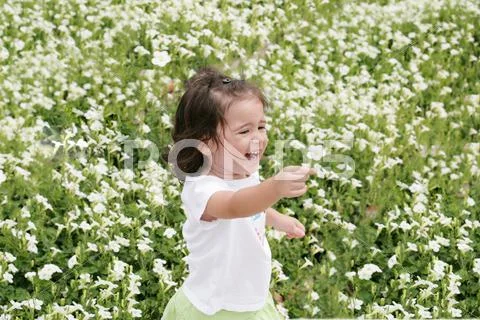 Baby girl happy in a garden of flowers Stock Photos