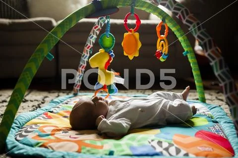 Baby girl lying on playmat at home Stock Photos