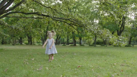 Baby girl running through the grass in garden in sunset sunlight. 库存影片 115905053