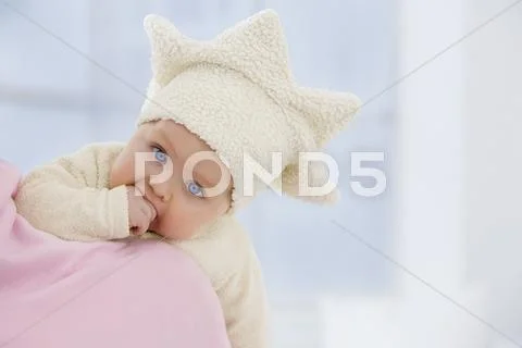 Baby Girl In Star Shape Hat With Finger In Mouth