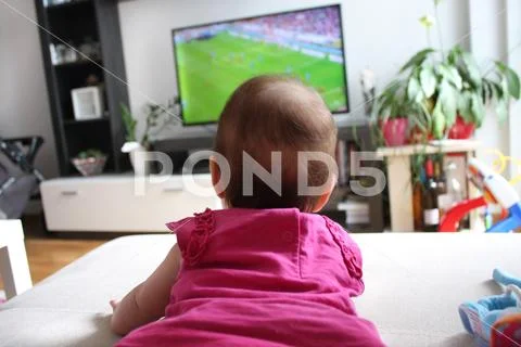 Baby girl watching a soccer on TV Stock Photos