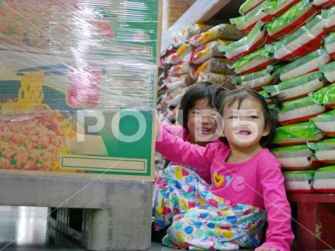 Baby girls, sisters, hiding behind big boxes at supermarket - hide and seek Stock Photos