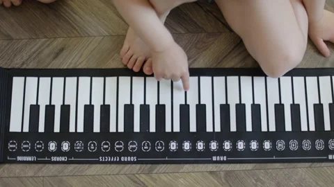Baby hands playing pushing keys electronic piano on wooden floor indoors high Stock Footage 211661925