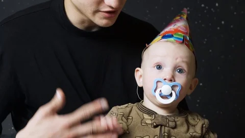 The baby has a birthday. The child in the cap sits on his father's hands. He is Stock Footage 88871153