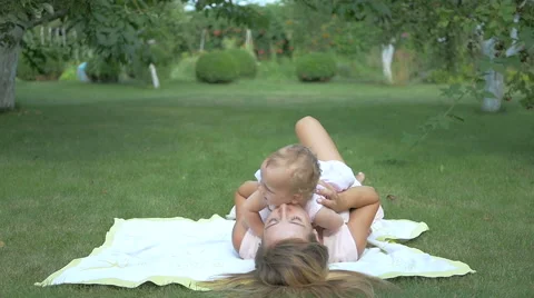 Baby with her mom lying on the rug in the garden. Stock Footage
