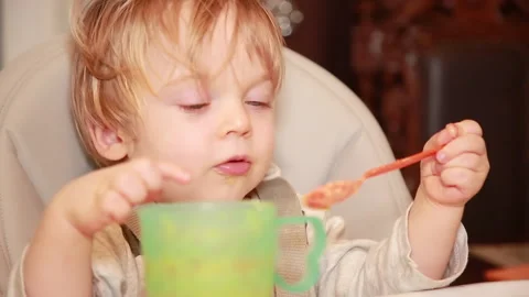 The baby himself eats porridge with a small spoon Stock Footage 147353333