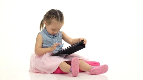 Baby is holding a computer in her hands and cliches, she is in a good mood Stock Footage 76749006