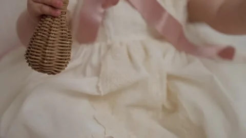 Baby holding wicker rattle while wearing lace ceremony dress Stock Footage 331333155