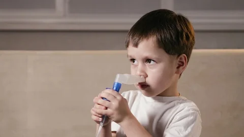 Baby inserts a nebulizer nozzle into the nose and inhales through the nose Vidéo 123906140