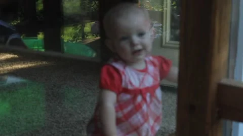 Baby inside window watching boy play Stock Footage 40204918