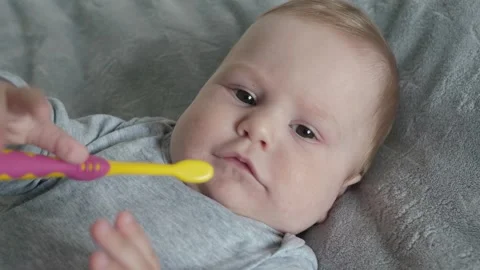 Baby joyfully exploring a vibrant array of colors with a toothbrush Stock Footage 305511788