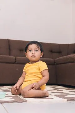 Baby kneeling in the living room of the house watching Stock Photos