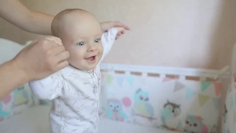 Baby learn to walk on the bed with my mother's help Stock Footage 80325419