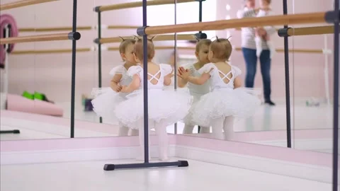 Baby learning ballet in studio with mirror reflection. Cute girl toddler dances Stock Footage 322001730
