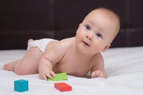Baby is learning to crawl on a bed Stock Photos