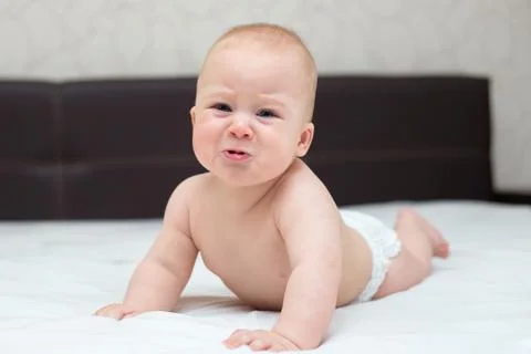 Baby is learning to crawl on a bed Stock Photos