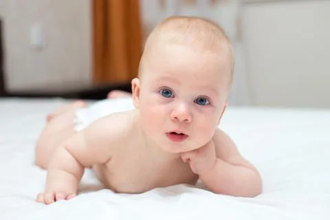 Baby is learning to crawl on a bed Stock Photos