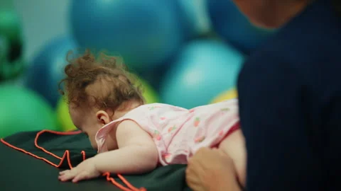 Baby learning to crawl during early intervention physical therapy session with Stock Footage 339788878