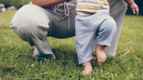 Baby learning to walk first step with mother on green grass, happy family baby Stock Footage 202080244