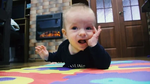 Baby learns to crawl. Lies on a multi-colored carpet Stock Footage 102031889