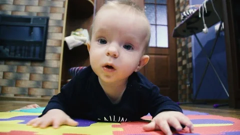 Baby learns to crawl. Lies on a multi-colored carpet Stock Footage 102031966