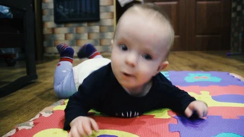 Baby learns to crawl. Lies on a multi-colored carpet Stock Footage 102032010