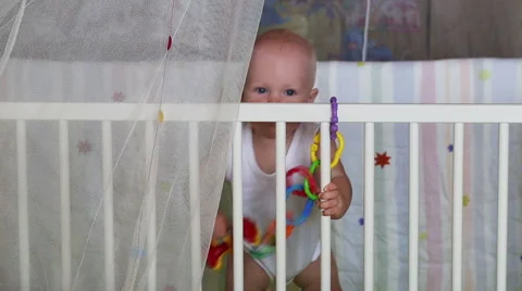 Baby learns to stand holding support in the crib Stock Footage 40940048