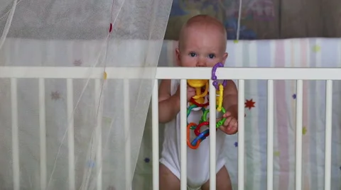 Baby learns to stand holding support in the crib Stock Footage 40944696