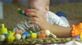 The baby lies on the bed look and play with toys . Close-up portrait view 4k or 4k+ Resolution