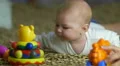 The baby lies on the bed look and play with toys . Close-up portrait view 4k or 4k+ Resolution