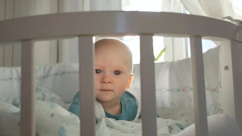 The baby lies in the crib by the window in the rays of a sunny day Video stock 127508545