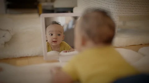A baby looking at their reflection in the mirror, full of wonder and Stock Footage 280317348