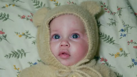 Baby is lying on a blanket and looking at camera. Close-up. Stock Footage 337538580
