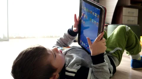 BABY is lying on the floor with a large touchscreen computer in the hands Stock Footage 59963881