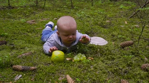 The baby is lying in the forest and eats the big Apple Видео 76391854