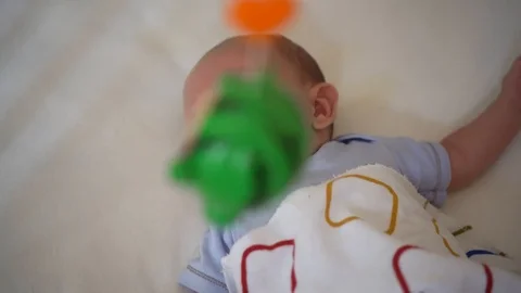 Baby lying in his bed, looking at toys Stock Footage 97690118