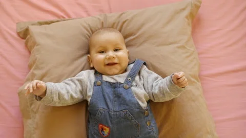 A baby lying on his bed smiles and looks at the camera, in France Stock Footage 213699771