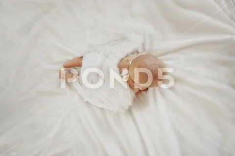 Baby is lying on his stomach on a white background with wings