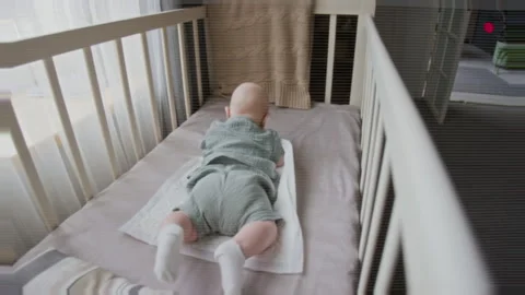 Baby Lying on Stomach in Crib Doing Tummy Time Exercises Vídeos de archivo 346594520