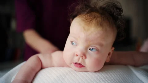 Baby lying on their tummy while an adult massages them and performs mobility Stock Footage 329397717
