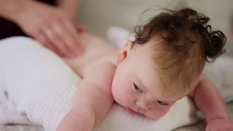 Baby lying on their tummy while an adult massages them and performs mobility 스톡 동영상 329401538